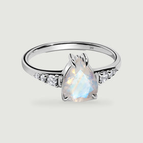 A polished white gold band surrounds a faceted pear-shaped moonstone with diamond accents.