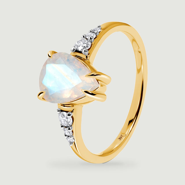 An angled yellow gold ring shows the raised moonstone setting and graduated round diamonds.