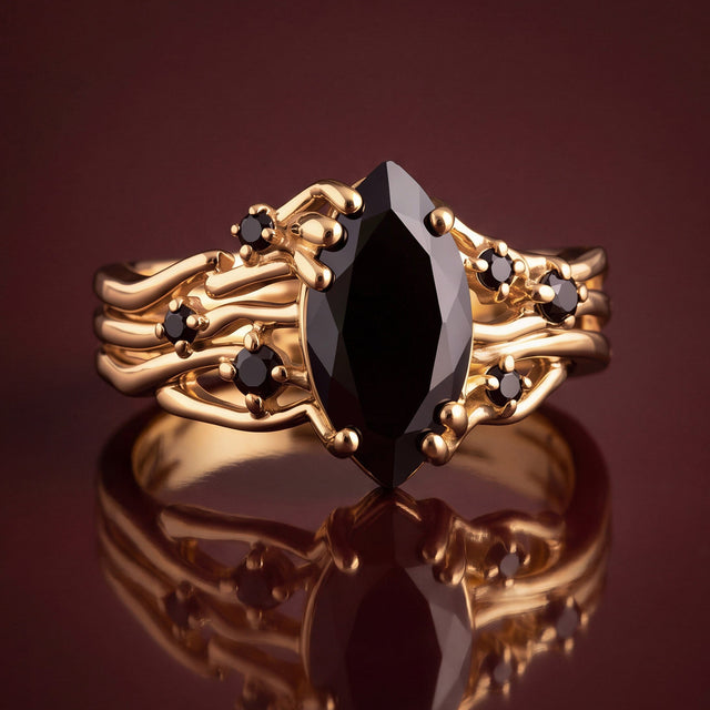 The yellow gold ring stands on a polished surface with its black stones reflected below.