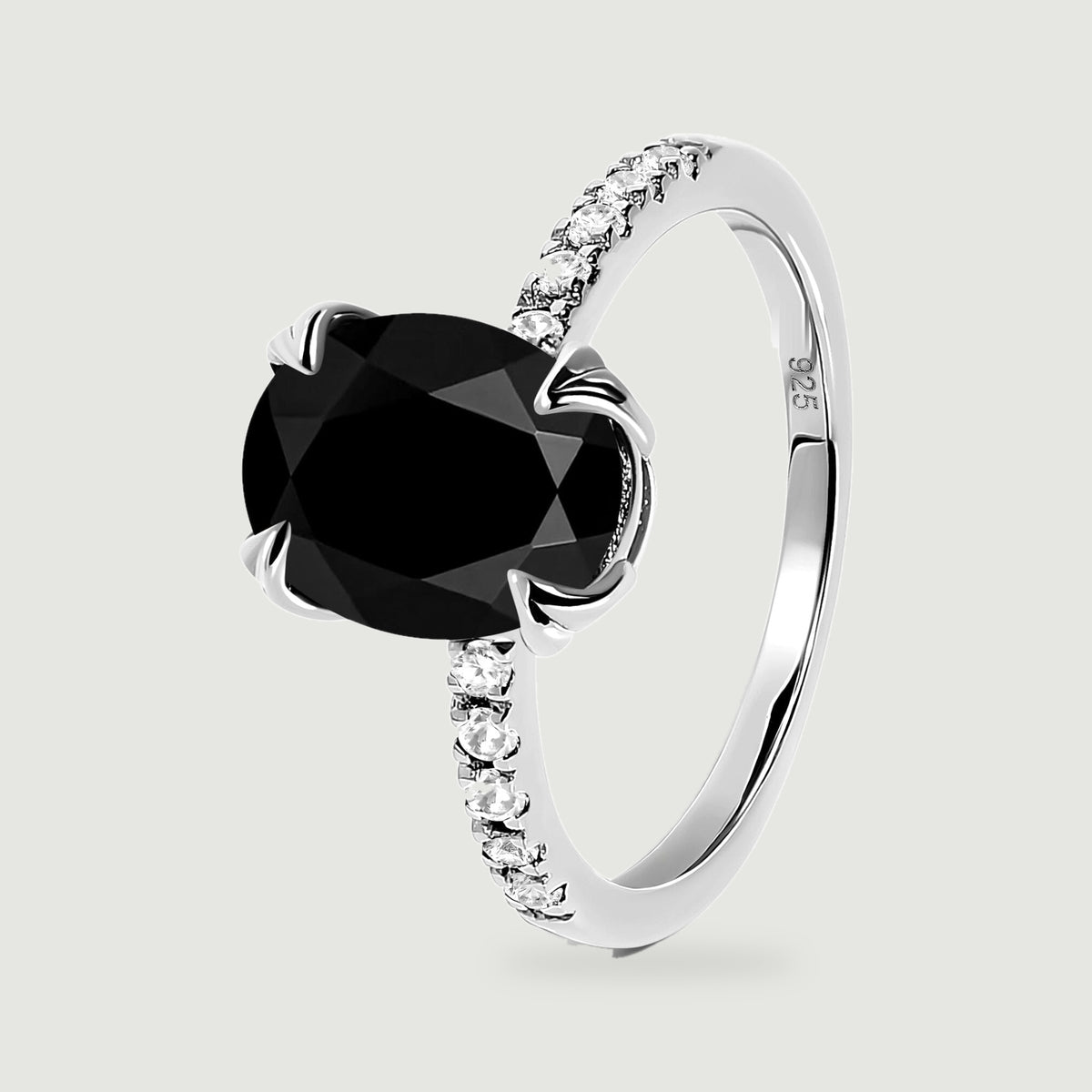The silver ring is shown upright at an angle, revealing the faceted black stone and the curve of the band.