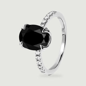 The silver ring is shown upright at an angle, revealing the faceted black stone and the curve of the band.