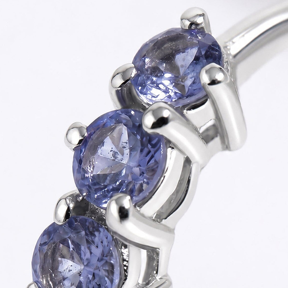 Round violet gemstone facets and polished silver-tone prongs fill this close-up.