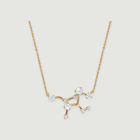 A yellow gold necklace displays a branching constellation centre with pale round stones against a light grey surface.