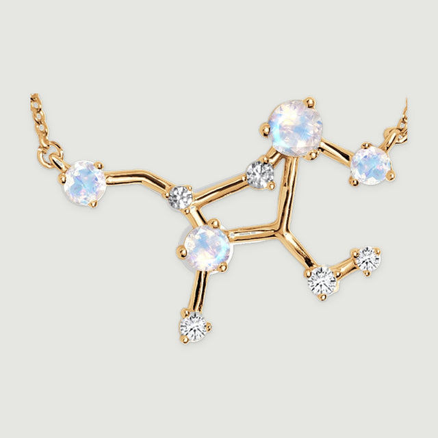 Round pale stones and small clear stones sit in yellow gold prongs along an open branching necklace centre.