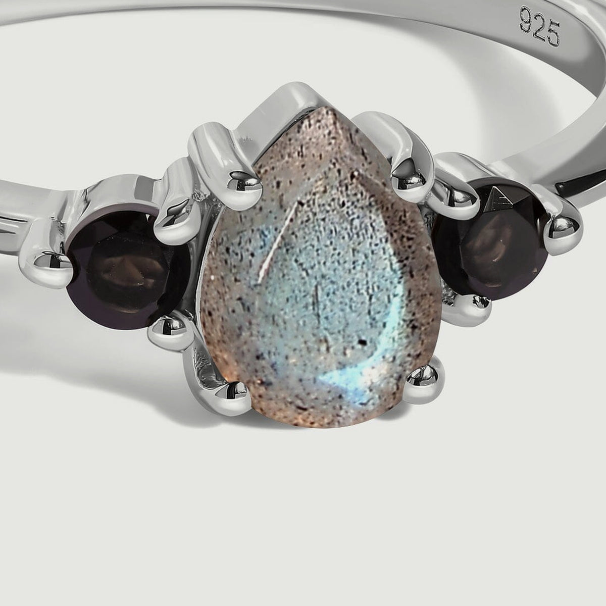 A close view shows the speckled pear-shaped labradorite and round black obsidian stones held in silver prongs.