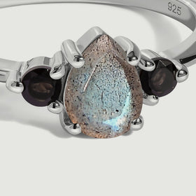 A close view shows the speckled pear-shaped labradorite and round black obsidian stones held in silver prongs.