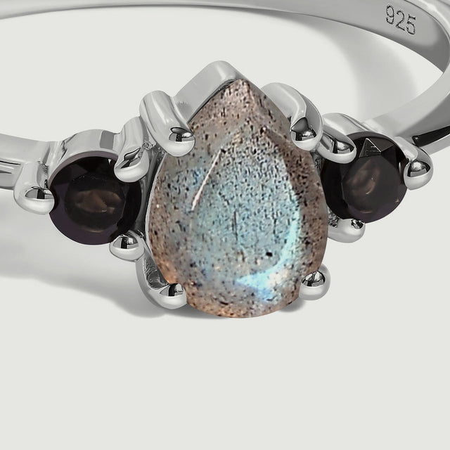 A close view shows the speckled pear-shaped labradorite and round black obsidian stones held in silver prongs.