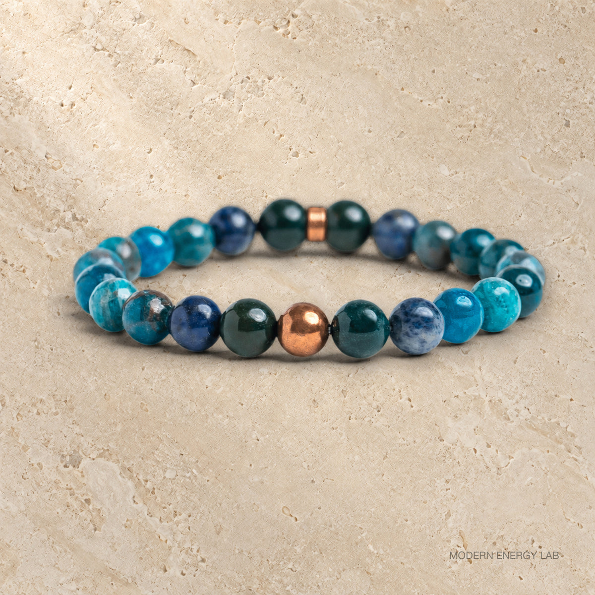 Blue apatite, bloodstone and dumortierite bracelet with smooth copper accents on travertine
