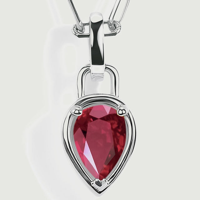 The pointed red ruby pendant is shown close up with silver-colored prongs and a smooth reflective bail.