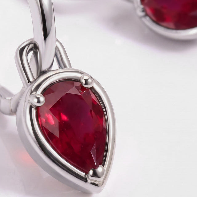 The pear-shaped red stone and polished white rhodium plated hoop fill this close view.