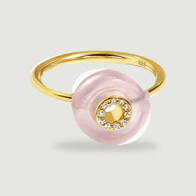 A yellow gold vermeil ring with a pale pink circular stone and a ring of clear stones rests on a light gray background.