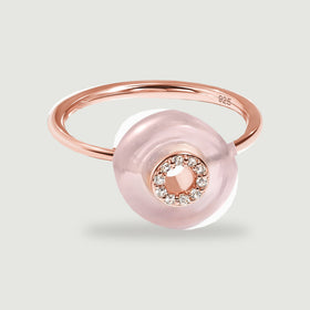 A rose gold vermeil ring displays a translucent pink disc and a sparkling circular center on a light gray surface.