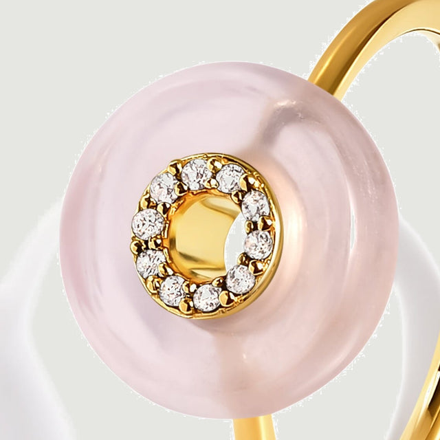 A close view shows the yellow gold setting and clear round stones inside the pink rose quartz disc.