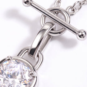 Macro view of a polished T-bar connector, chain links, and faceted clear gemstone setting.