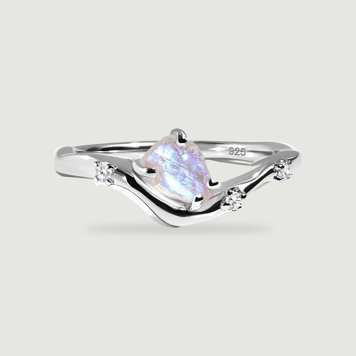A sterling silver wishbone ring holds a rough moonstone and three small clear stones on a light gray surface.