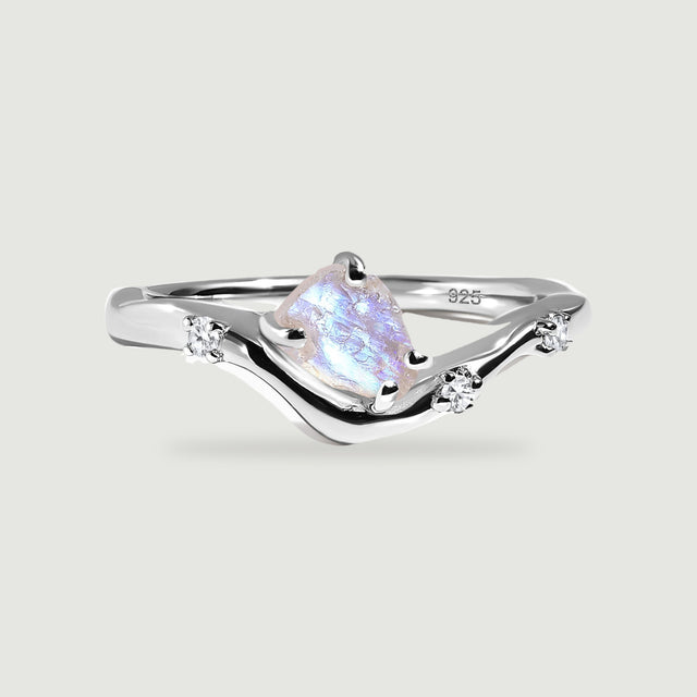 A sterling silver wishbone ring holds a rough moonstone and three small clear stones on a light gray surface.