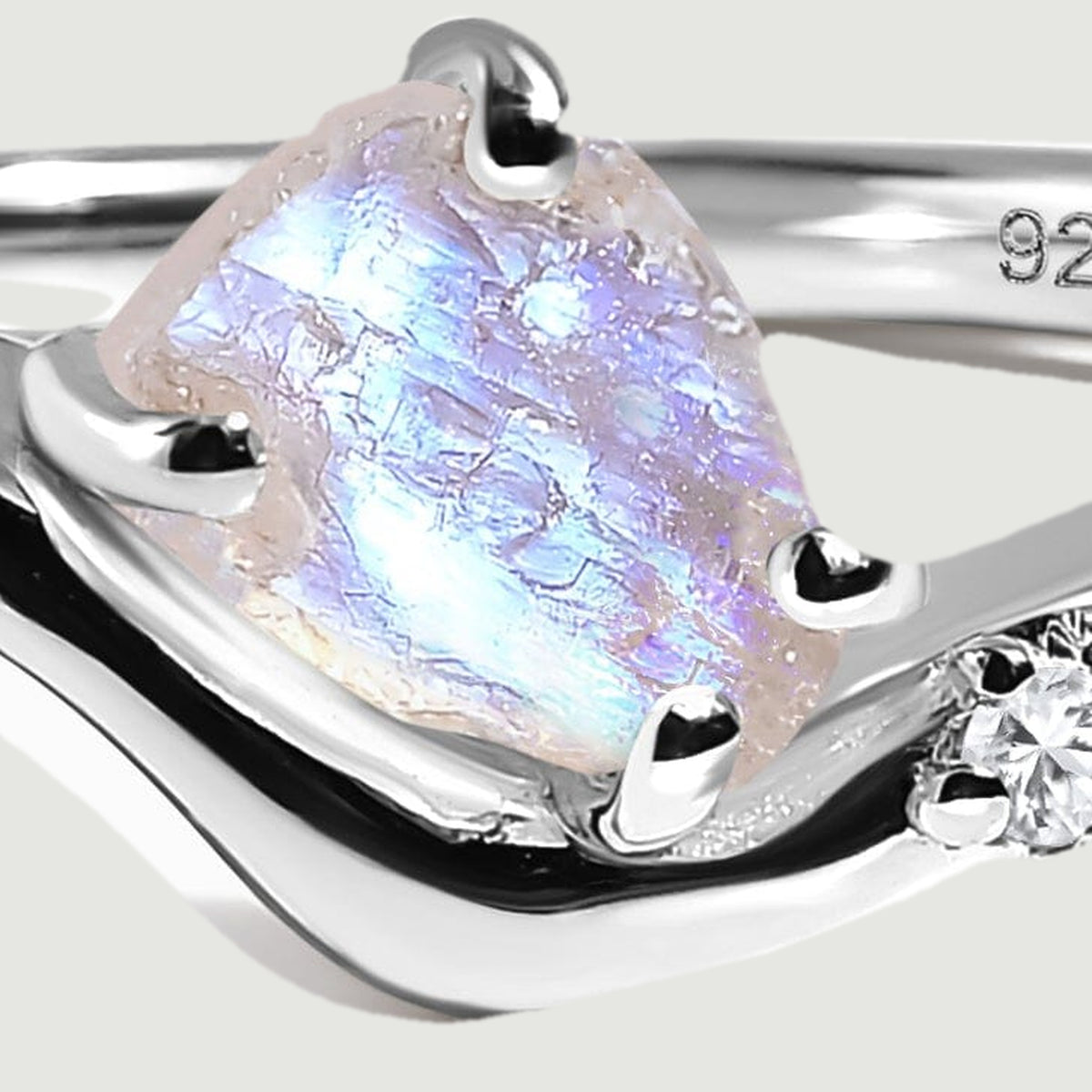 A close view shows the moonstone texture, silver prongs, and a clear accent stone along the wishbone curve.