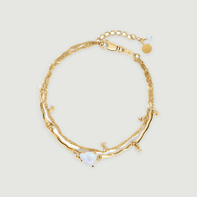 A yellow gold vermeil bracelet is centered on light gray with a pale moonstone, curved polished links and an extension chain.