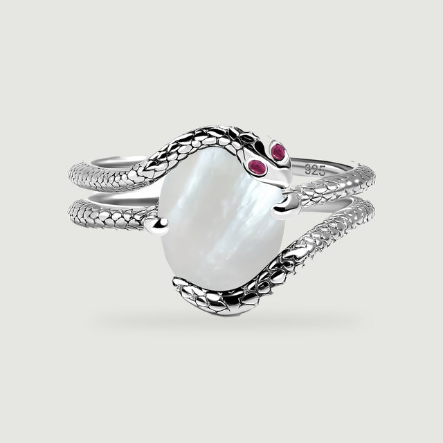 A silver wrap ring shows a pearly oval center framed by textured bands on a light gray surface.