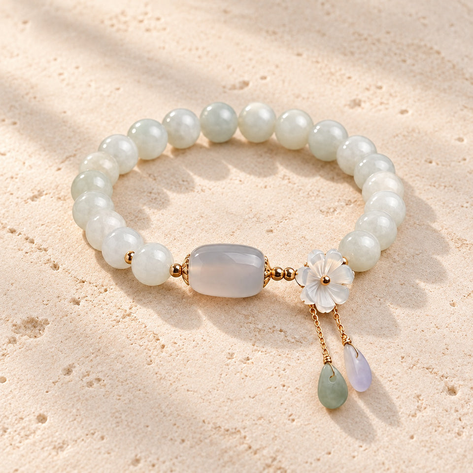 Illustrative styling of the white jade flower-and-drop bracelet on pale travertine; not a product color or size reference.